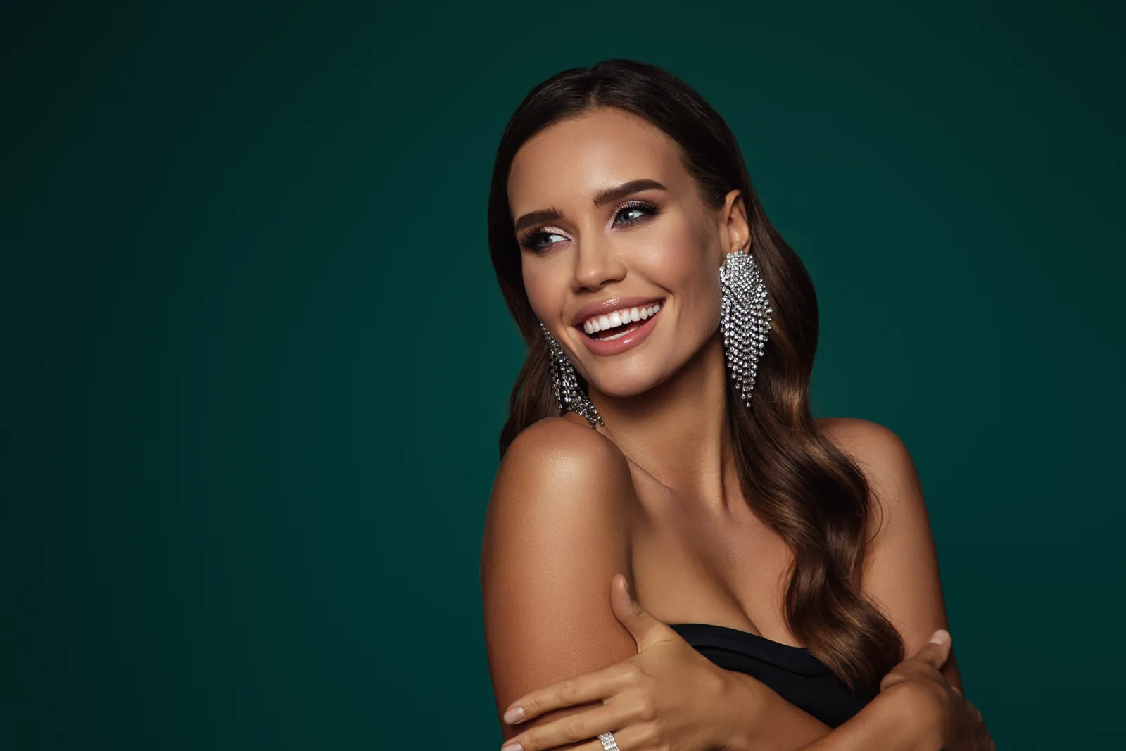 Smiling woman with long dark hair and statement earrings, smile makeovers in Essex