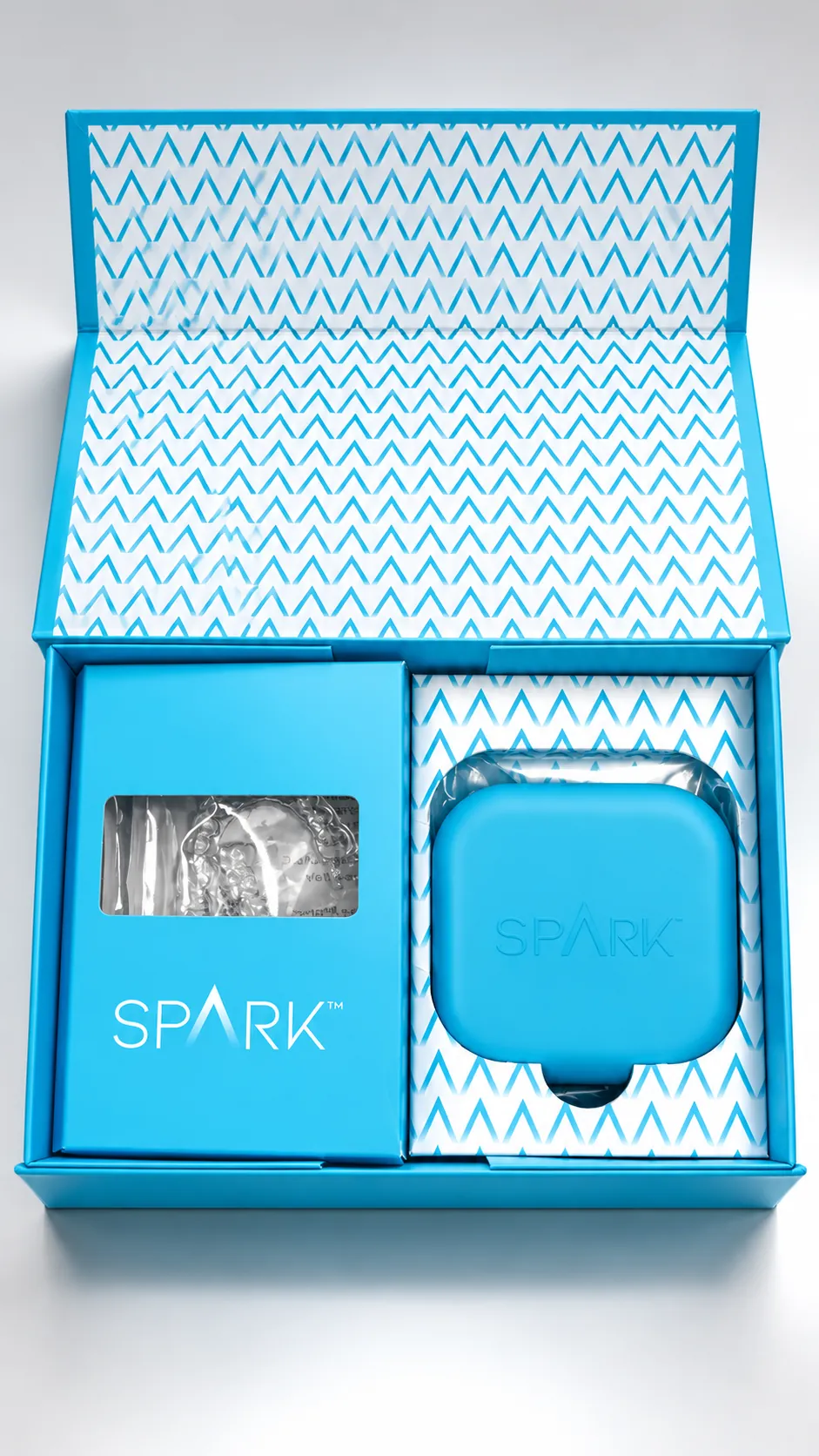 Open Spark presentation box holding aligners and a blue Spark aligner case