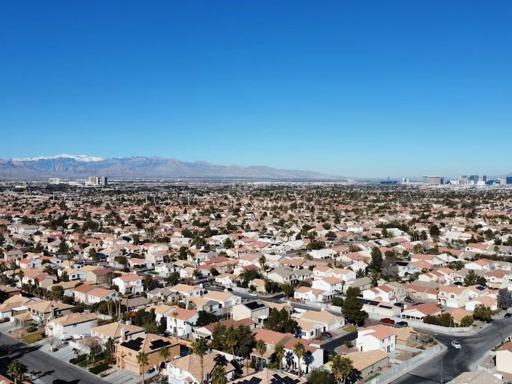 Aerial view of Las Vegas neighborhoods with snow-capped mountains and the Strip in the distance