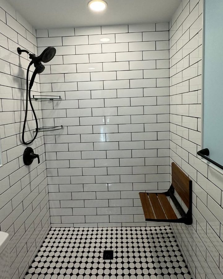 After: the same alcove as a walk-in shower with white subway tile, a fold-down teak seat and a black-and-white mosaic floor