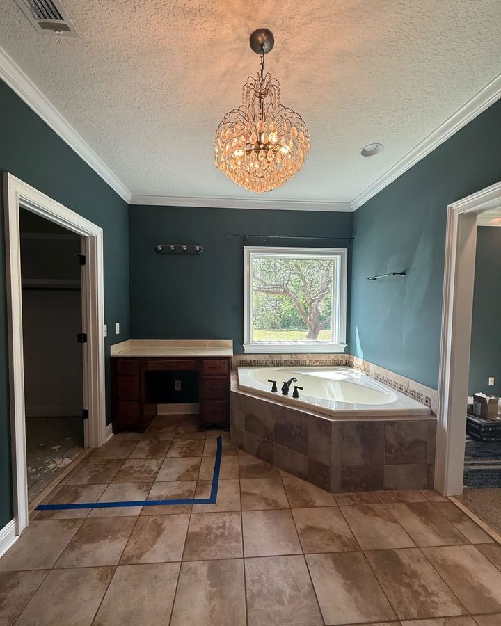 Before: master bathroom with a corner garden tub, dark green walls and brown tile floor