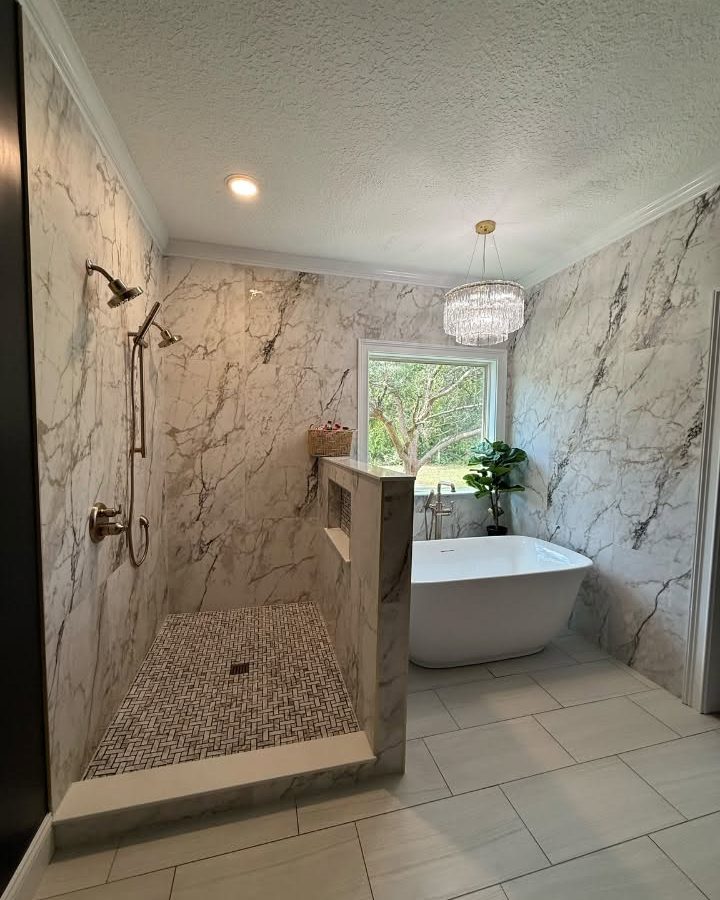After: the same master bathroom with a marble-look walk-in shower, a freestanding tub and light tile floor