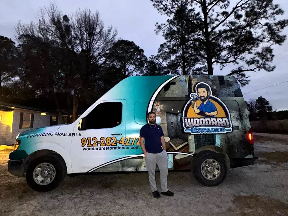 Colby Woodard standing beside the Woodard Restoration van